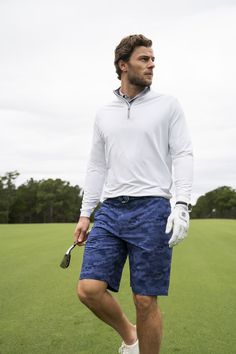 a man standing on top of a lush green field holding a golf racquet