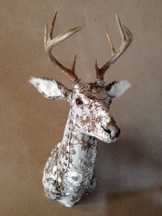 a ceramic deer head with antlers and flowers on it's body, against a tan background