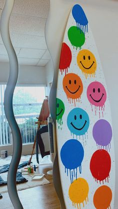 a surfboard with different colored smiley faces on it's side in an office