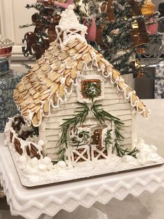 a gingerbread house is decorated with icing and pine cones for the holiday season