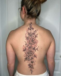 a woman's back tattoo with flowers and leaves on her left side ribcage