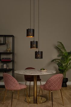 a dining room table with pink chairs and a white marble top, hanging from the ceiling