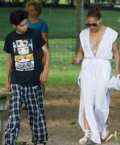 a woman in a white dress walking next to two boys