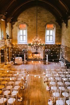 an indoor venue with rows of chairs and candles on the floor, surrounded by string lights