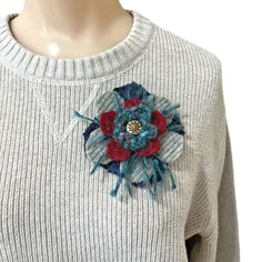 a woman wearing a sweater with a flower on it