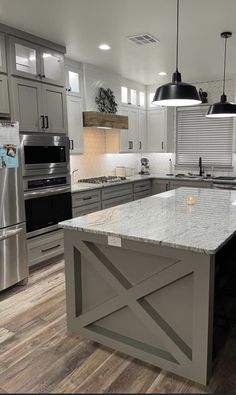 a large kitchen with an island in the middle and stainless steel appliances on both sides