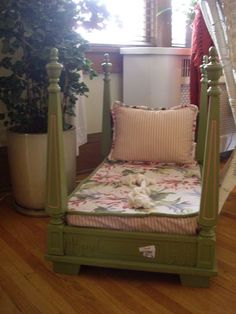 a green bed frame sitting on top of a hard wood floor next to a potted plant