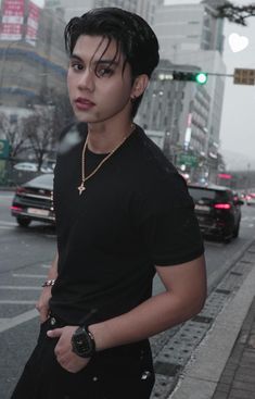 a man in black shirt standing on street next to cars