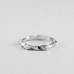 a white gold wedding band with twisted leaves on the side, set against a plain background