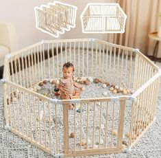 a baby sitting in a white crib on the floor