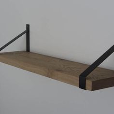 a wooden shelf with two black metal brackets