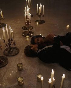 a person laying on the ground surrounded by candles