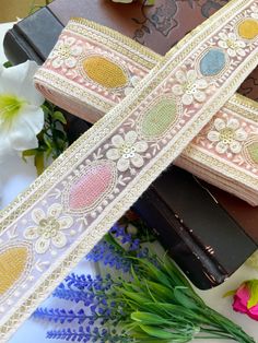 two decorative ribbons on top of each other next to flowers and chocolate bar wrappers