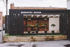 an industrial building with plants in the front and behind it's doors that say industry beans