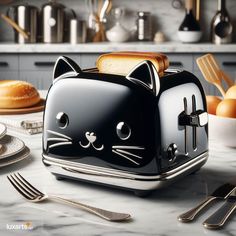 a black cat toaster sitting on top of a counter next to silverware and utensils