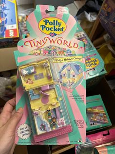 a person holding up a tiny world dollhouse in its package with the box open