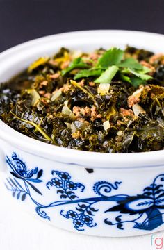 a white bowl filled with greens and meat