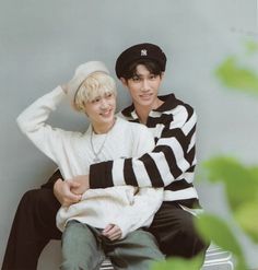 two young men sitting on top of each other wearing black and white striped sweaters