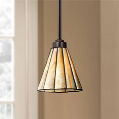 a light fixture hanging from a ceiling in a living room with beige walls and windows