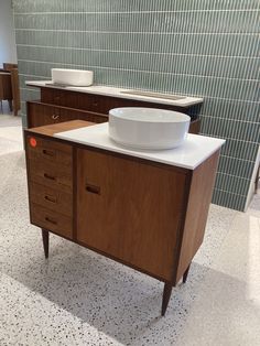 a bathroom sink sitting on top of a wooden cabinet in front of a tiled wall