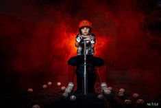 a young boy sitting on top of a baseball bat in front of a red background