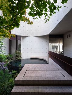 the stairs lead up to an indoor swimming pool in front of a white wall and trees