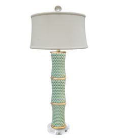 a green and white lamp with a shade on it's side, sitting next to a