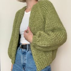 a woman is wearing a green cardigan sweater