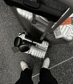 a person standing with their feet up on an airport luggage bag and looking down at the floor