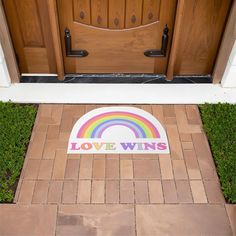 a door mat with the words love wins on it in front of a wooden door