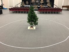 a small christmas tree sitting on top of a table in a room filled with red chairs