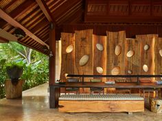 a wooden bench sitting in front of a wall covered with wood circles on it's side