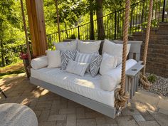 a porch swing with pillows on it