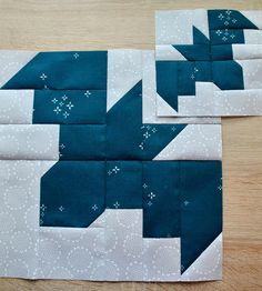 two pieces of blue and white quilted fabric sitting on top of a wooden table