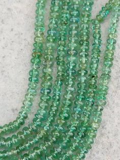 green glass beads are lined up on the ground