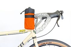 an orange and black bag is attached to the handlebars of a white bicycle