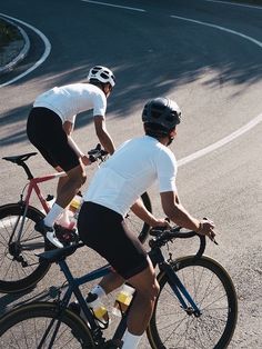 two bicyclists are riding down the road in front of each other on their bikes