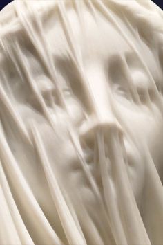 the face of a statue is covered in white cloth