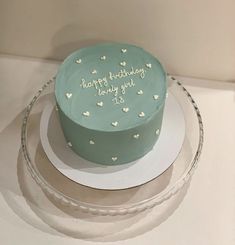 a birthday cake with hearts on it sitting on top of a glass platter in front of a white wall