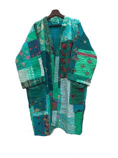 a green jacket with patchwork on the front and back, hanging from a wooden hanger