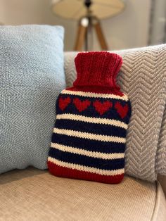 a knitted hot water bottle sitting on top of a couch next to two pillows