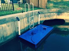 a blue table sitting in the middle of a body of water next to a fence