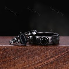 two black rings sitting on top of a wooden table next to each other and one ring has a diamond in the middle