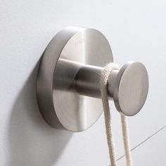 a close up of a metal hook on a white wall with rope attached to it