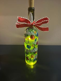 a bottle that is sitting on a table with a red ribbon around it and lights in the bottom