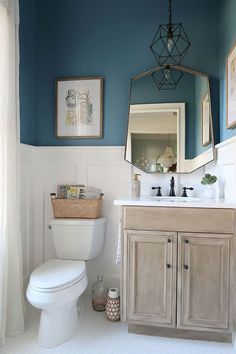 a white toilet sitting under a bathroom mirror next to a wooden sink vanity in a bathroom