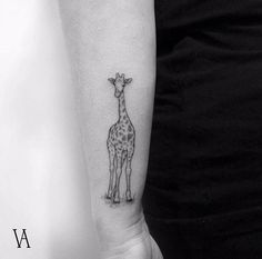 a small giraffe tattoo on the arm