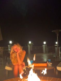 a woman sitting in front of a fire pit