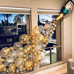 the balloon arch is decorated with gold, silver and white balloons in front of a living room window