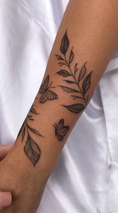 a woman's arm with tattoos on it and butterflies flying over the top of her arm